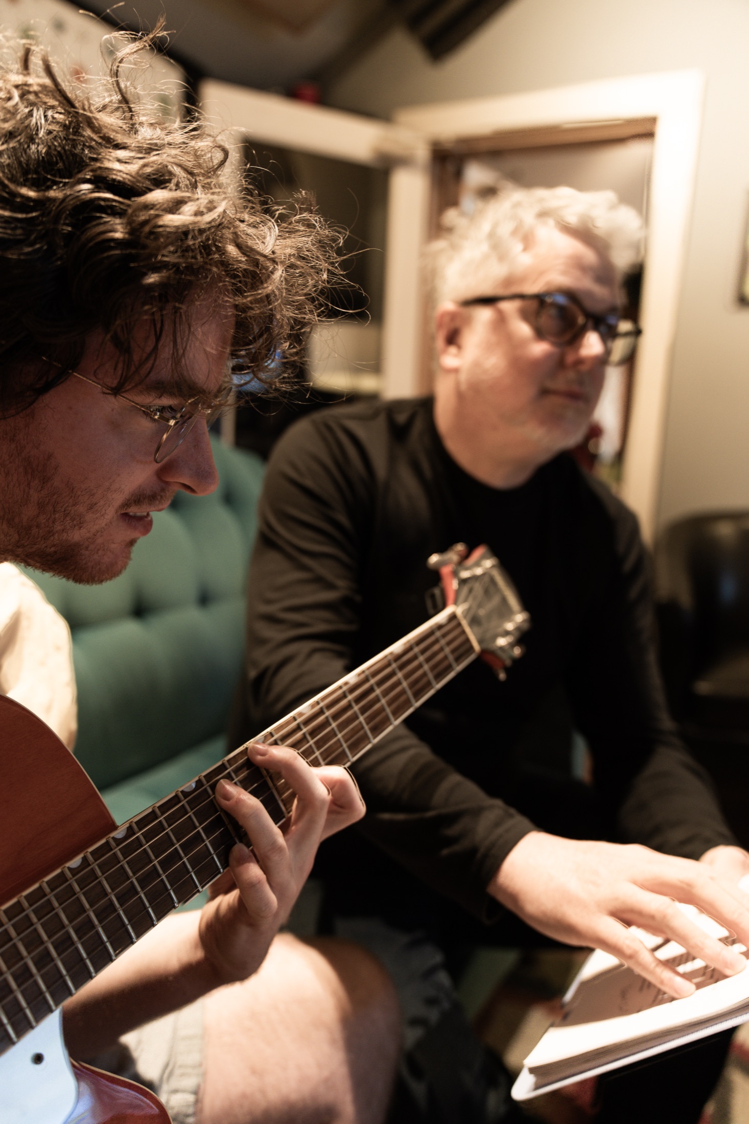 An artist with acoustic guitar working through a song with Tom Michael.